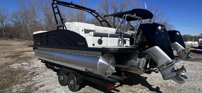 Slide: The Image of 2024 Harris Sunliner 250 Sport pontoon boat with dual outboard engines on a trailer. - 3