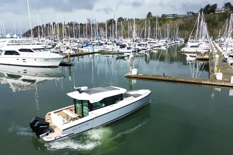 Slide: The Image of 2026 Saxdor 320 GTC boat cruising in a marina with numerous docked yachts. - 19