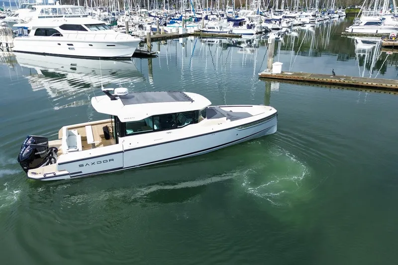 Slide: The Image of 2026 Saxdor 320 GTC boat cruising in a marina with yachts in the background. - 20