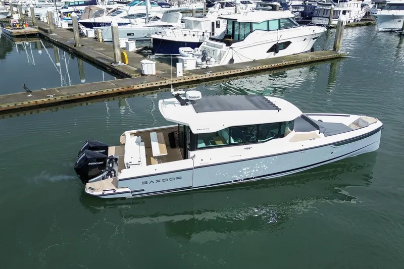 Slide: The Image of 2026 Saxdor 320 GTC boat docked at a marina, featuring sleek design and twin Mercury engines. - 23