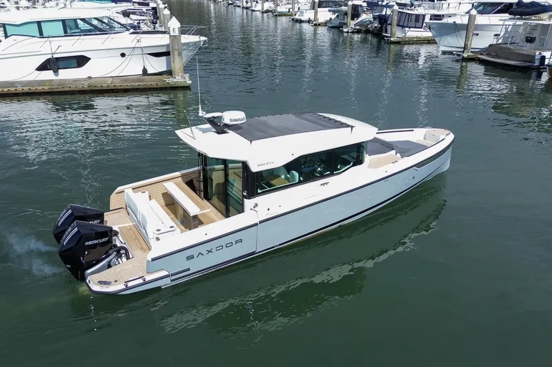 Slide: The Image of 2026 Saxdor 320 GTC boat docked in marina, featuring sleek design and twin Mercury engines. - 26