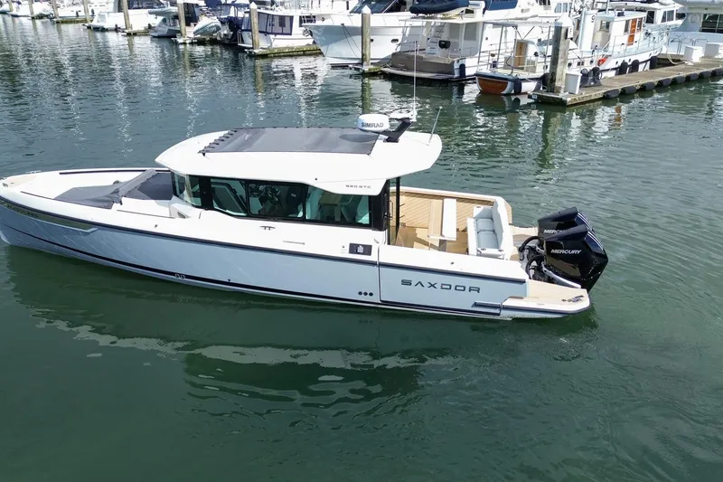 Slide: The Image of 2026 Saxdor 320 GTC boat docked in marina, featuring sleek design and Mercury outboard engine. - 28