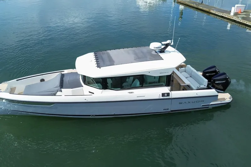 Slide: The Image of 2026 Saxdor 320 GTC boat on calm water, featuring sleek design and twin Mercury engines. - 32