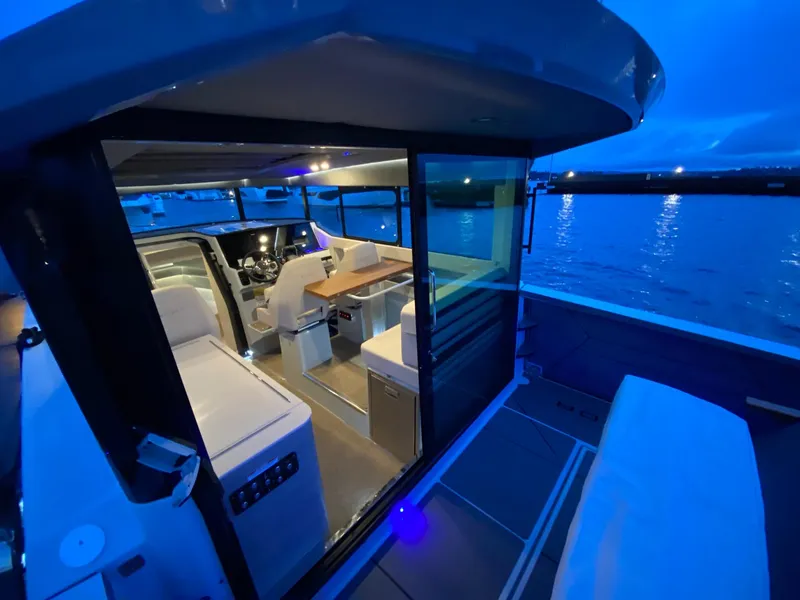 Slide: The Image of Interior view of 2025 Saxdor 320 GTC yacht at dusk, featuring modern seating and table. - 9