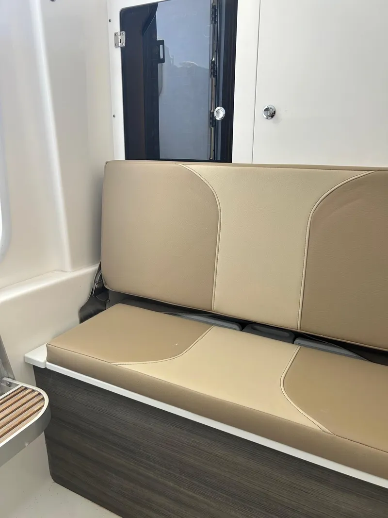 Slide: The Image of 2024 Sea Pro 322 Offshore boat interior seating with beige cushions. - 11