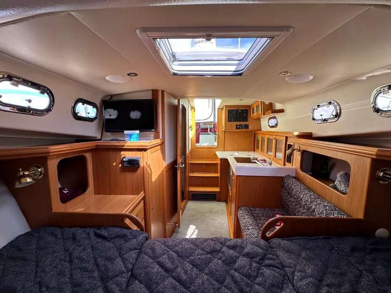 Slide: The Image of Interior of 2016 Marlow Pilot 31 boat with wood finish, cozy seating, and ample storage. - 22