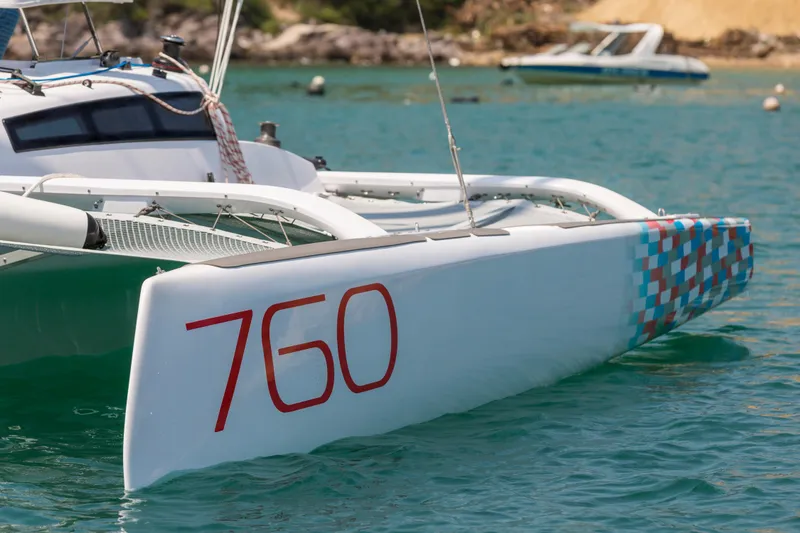 Slide: The Image of Modern Corsair 760 trimaran sailing on turquoise waters, showcasing sleek design and vibrant graphics. - 12
