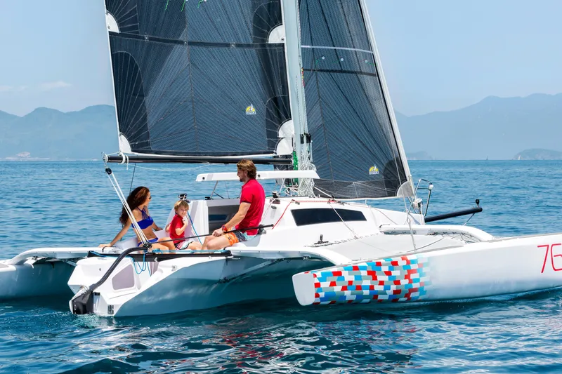 Slide: The Image of Family enjoying a sail on a 2026 Corsair 760 trimaran in clear blue waters. - 13