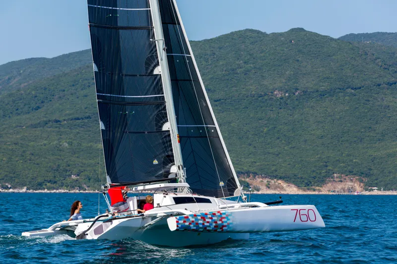 Slide: The Image of Sleek Corsair 760 sailboat gliding on blue waters, 2026 model, with lush green hills in background. - 16