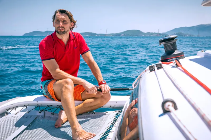 Slide: The Image of Man relaxing on a Corsair 760 sailboat, 2026 model, in sunny ocean setting. - 19
