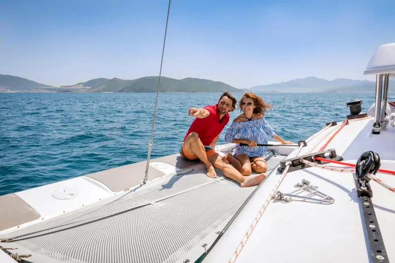 Slide: The Image of Couple enjoying a sunny day on a 2026 Corsair 760 sailboat, surrounded by scenic ocean views. - 23