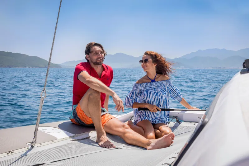 Slide: The Image of Couple enjoying a sunny day on a 2026 Corsair 760 sailboat, surrounded by scenic ocean views. - 25