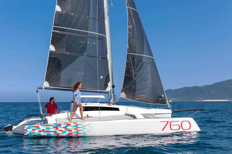 Slide: The Image of Sleek 2026 Corsair 760 sailboat gliding on blue ocean with two people onboard. - 30