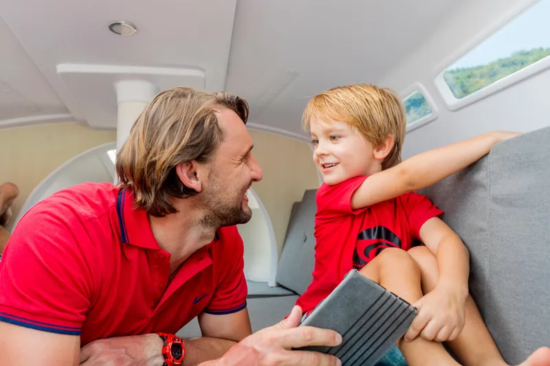Slide: The Image of Father and son smiling inside a 2026 Corsair 760 sailboat cabin. - 39
