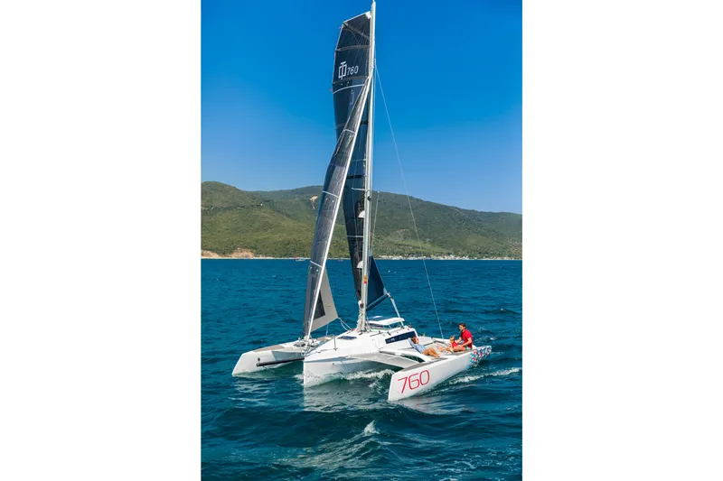 Slide: The Image of Sleek 2026 Corsair 760 trimaran sailing on blue ocean near green hills. - 43