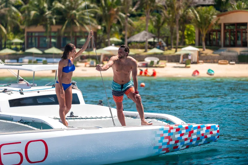 Slide: The Image of Couple enjoying a sunny day on a 2026 Corsair 760 sailboat near a tropical beach. - 7
