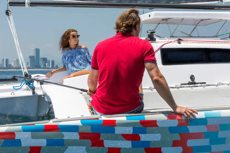 Slide: The Image of Couple enjoying a sunny day on a 2026 Corsair 760 sailboat with city skyline backdrop. - 8