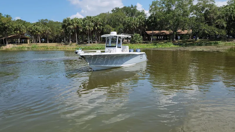 Slide: The Image of 2023 Sea Hunt Gamefish 27 boat cruising on a calm lake with a forested shoreline. - 29
