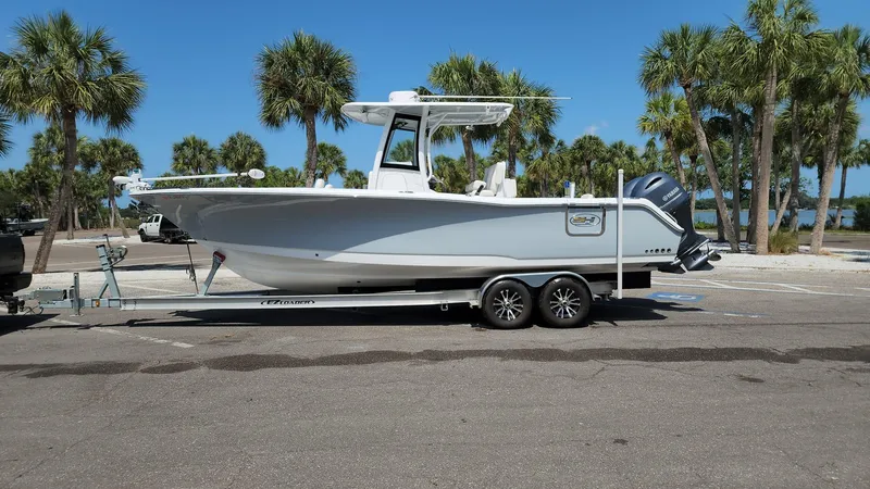 Slide: The Image of 2023 Sea Hunt Gamefish 27 boat on trailer in sunny parking lot with palm trees. - 3