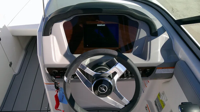 Slide: The Image of 2024 Chaparral 23 SSI SPORT boat dashboard with steering wheel and Simrad display. - 8