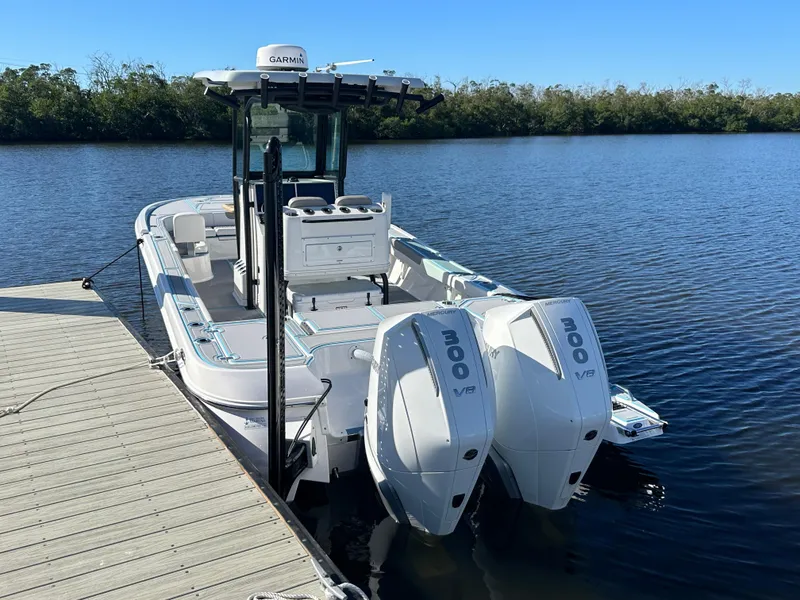 Slide: The Image of 2024 Caymas 281 HB boat docked with twin 300 HP engines on a calm lake. - 6