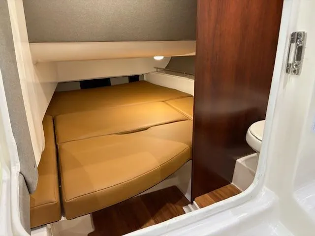 Slide: The Image of 2024 Chaparral 310 OSX cabin interior with tan cushions and wood accents. - 10
