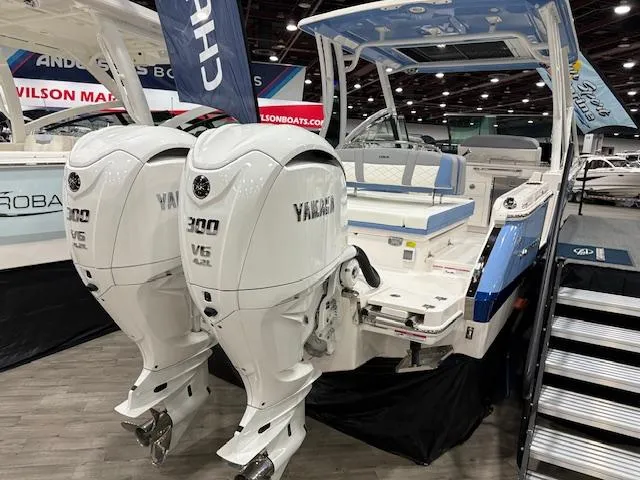 Slide: The Image of 2024 Chaparral 310 OSX boat with dual Yamaha V6 300 engines displayed indoors. - 2