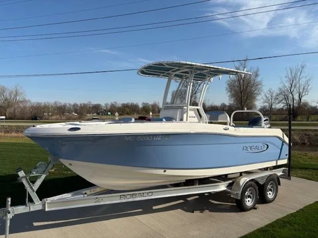Slide: The Image of 2024 Robalo R202EX boat on trailer, blue hull, parked on concrete driveway. - 1