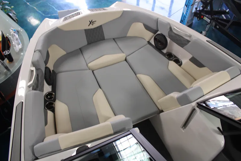 Slide: The Image of 2024 MasterCraft XT24 boat interior with gray and beige seating, cup holders, and speakers. - 6