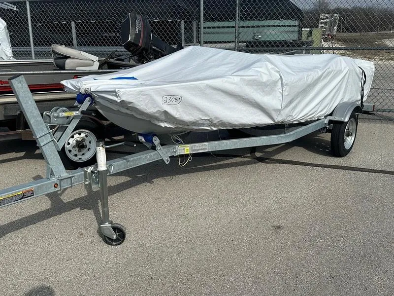 The Image of Covered Veer V13 boat on trailer, 2023 model, parked on asphalt near chain-link fence. - 1