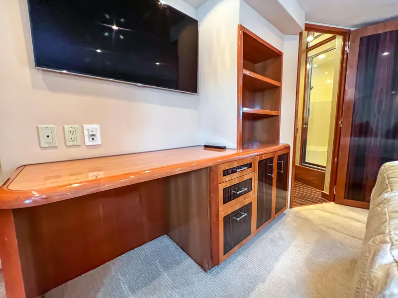 Slide: The Image of 2007 Hatteras 68 Convertible interior with TV, wooden desk, and shelving. - 26