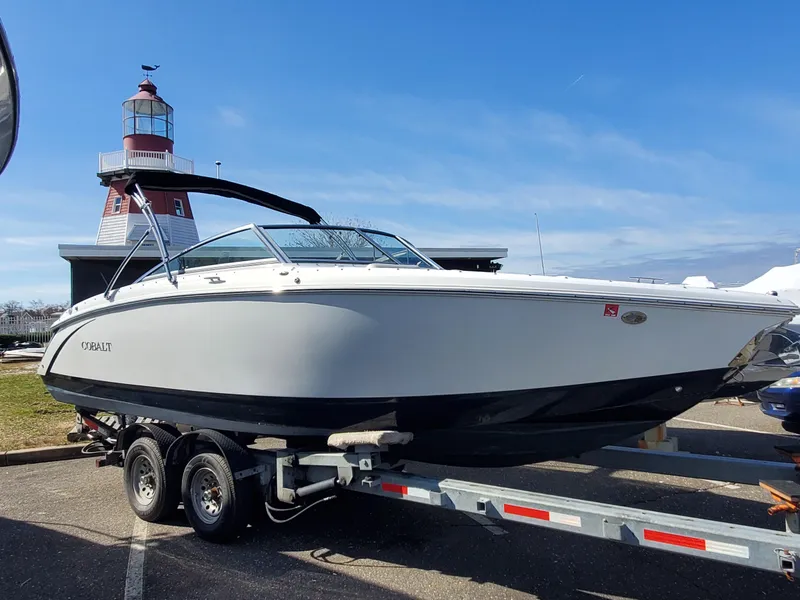 Slide: The Image of 2016 Cobalt R5 boat docked with black cover on a calm lake. - 2