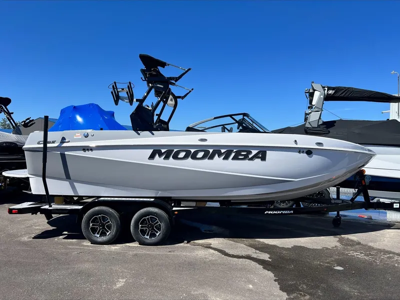 Slide: The Image of 2024 Moomba Craz boat on trailer, side view, parked outdoors under clear blue sky. - 1