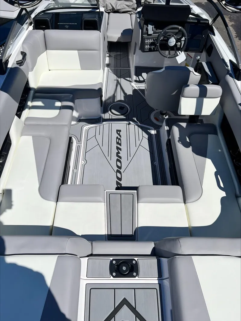 Slide: The Image of 2024 Moomba Craz boat interior with gray and white seating, steering wheel, and control panel. - 3