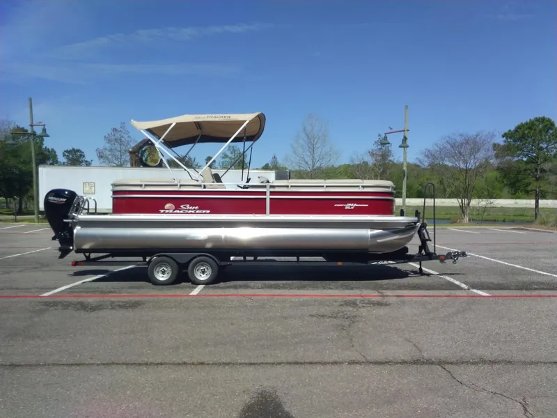 Slide: The Image of 2024 Sun Tracker Party Barge 24 DLX pontoon boat on trailer in parking lot. - 4