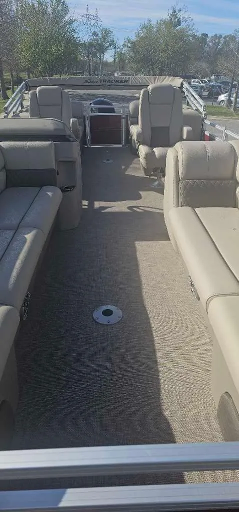 Slide: The Image of 2024 Sun Tracker Party Barge 24 DLX interior with beige seating and spacious layout. - 2