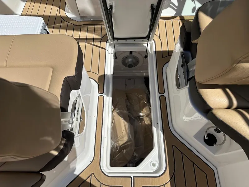 Slide: The Image of 2024 Sea Ray SDX 250 boat interior storage compartment with tan seats and teak flooring. - 22