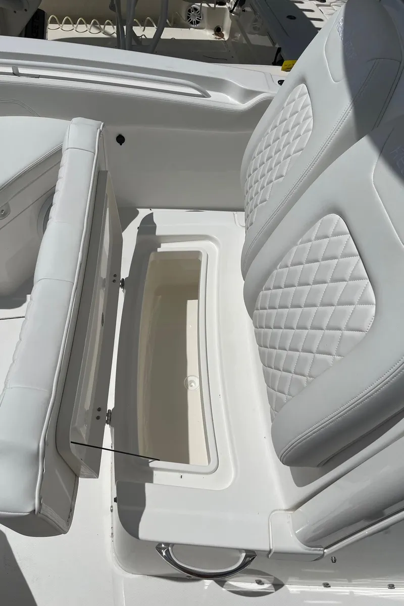 Slide: The Image of 2024 Regulator 24XO boat with open storage compartment and cushioned seating. - 13