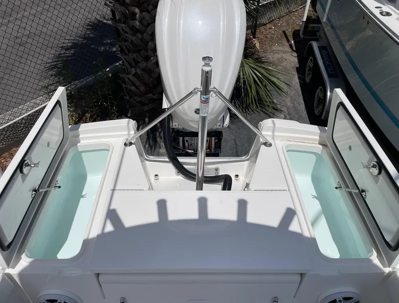 Slide: The Image of 2024 Regulator 24XO boat stern with open storage compartments and outboard motor. - 16