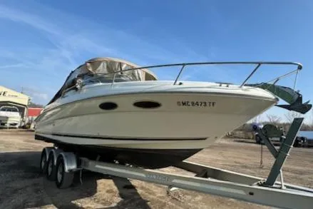 The Image of 1997 Sea Ray 280 boat on a trailer under a clear blue sky. - 0