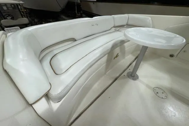 Slide: The Image of 1997 Sea Ray 280 boat interior with white cushioned seating and small table. - 10
