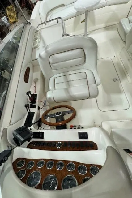 Slide: The Image of 1997 Sea Ray 280 boat cockpit with white seating and wooden dashboard. - 14