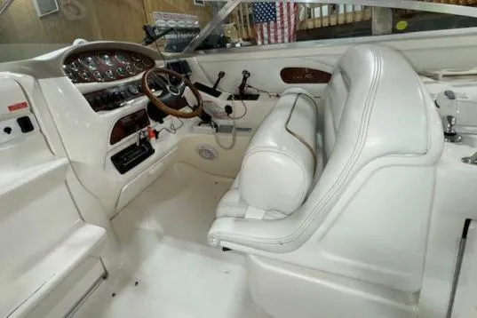 Slide: The Image of 1997 Sea Ray 280 boat cockpit with white leather seats and wooden steering wheel. - 20