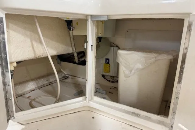 Slide: The Image of 1997 Sea Ray 280 boat interior storage compartment with plumbing and electrical components. - 25