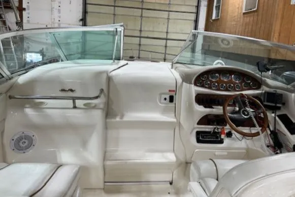Slide: The Image of Interior cockpit of a 1997 Sea Ray 280 boat with white seating and wooden dashboard. - 26