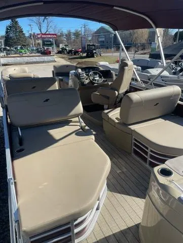 Slide: The Image of 2023 Starcraft CX 25 RL Tritoon boat interior with beige seating and steering console. - 2