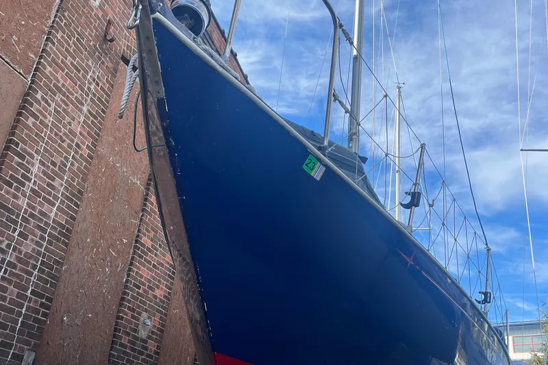 Slide: The Image of 1980 C&C 34 sailboat with blue hull docked against a brick wall. - 3