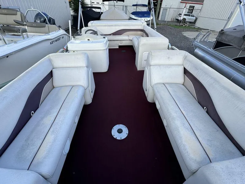 Slide: The Image of 2001 Godfrey Sweetwater pontoon boat interior with white seating and maroon carpet. - 2