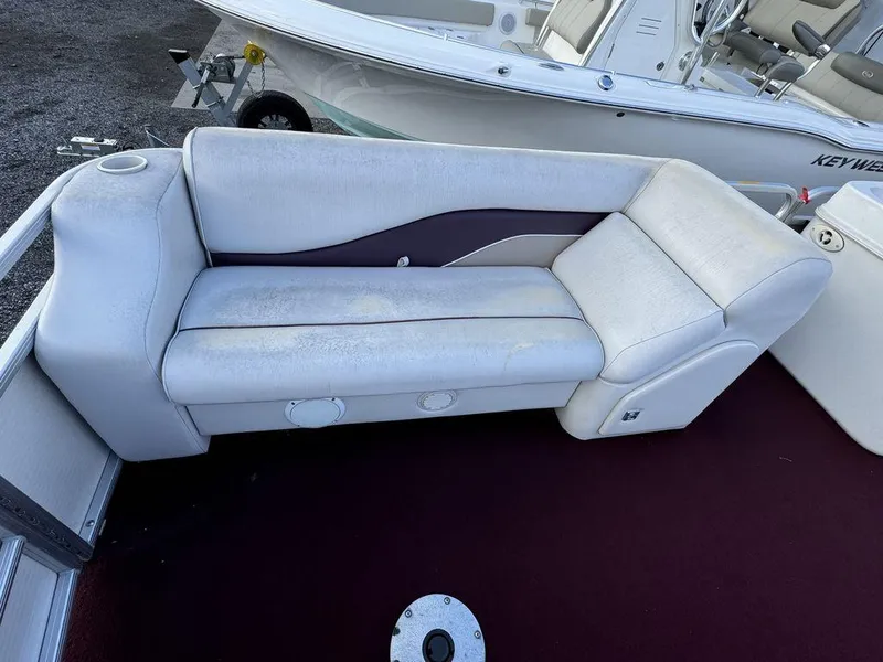 Slide: The Image of 2001 Godfrey Sweetwater boat seat with white upholstery on a maroon deck. - 3