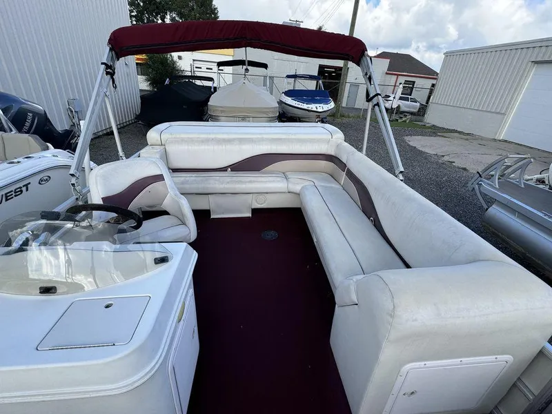 Slide: The Image of 2001 Godfrey Sweetwater pontoon boat with maroon canopy and white seating, docked outdoors. - 4